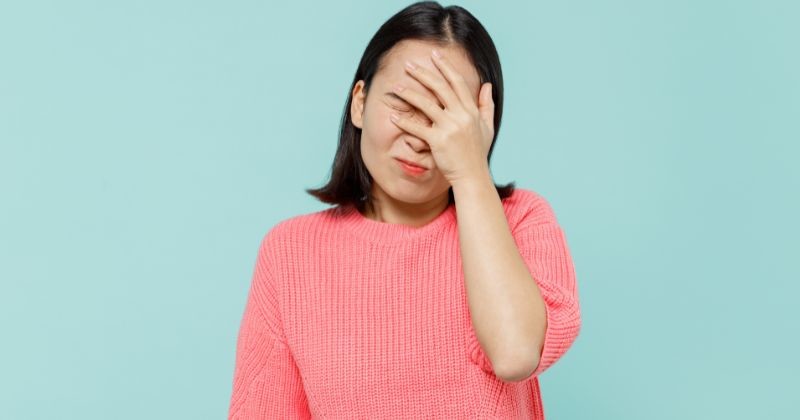 핑크색 스웨터를 입은 20대의 젊은 미소짓는 행복한 여성은 얼굴에 손을 얹고 얼굴에 손을 얹고 파스텔톤의 옅은 파란색의 배경스튜디오 사진을 찍었다. / 셔터스톡