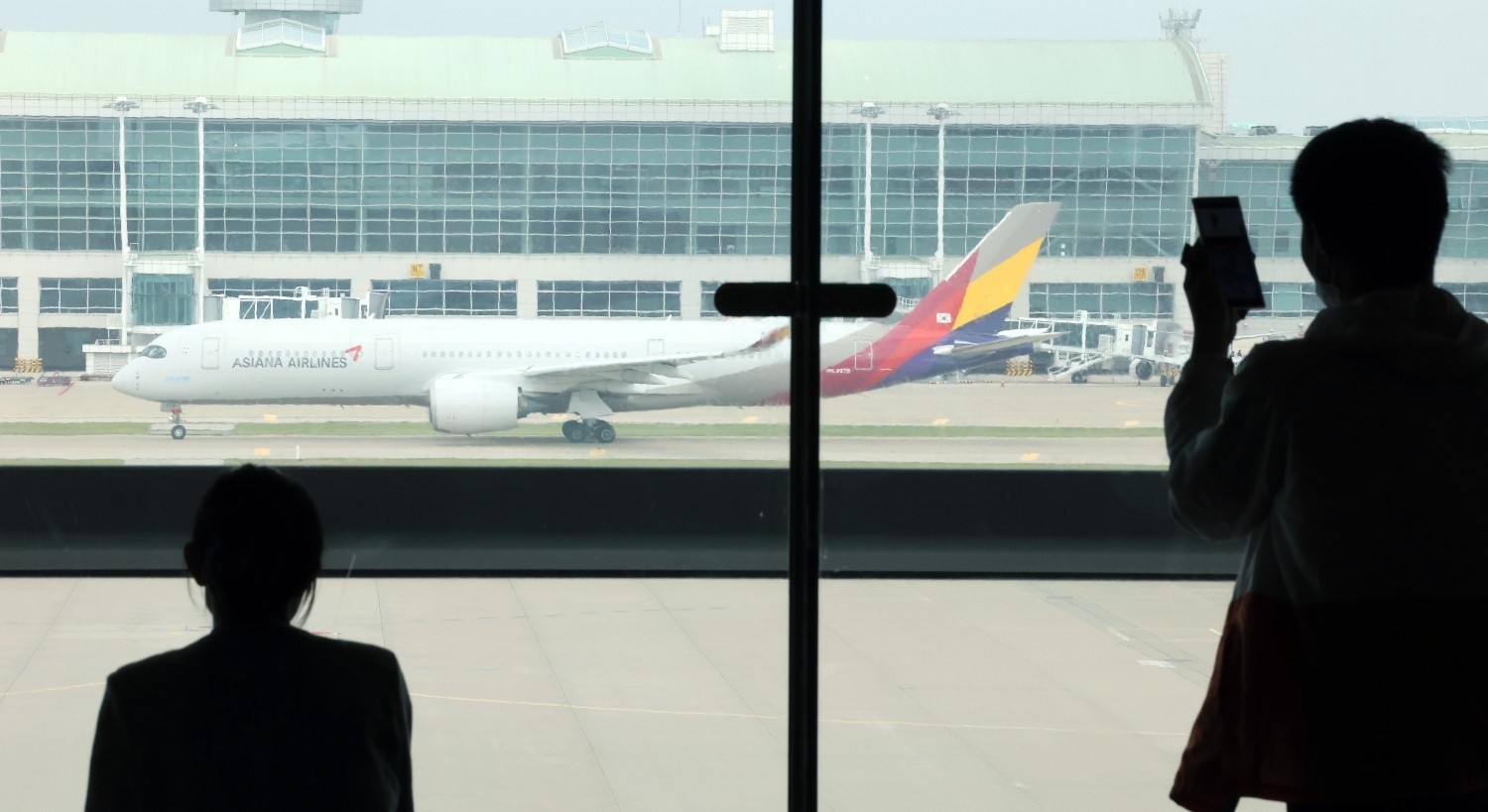 공항 창밖으로 비행기가 보이는 가운데 여행객들이 출국을 기다리고 있다. / 뉴스1