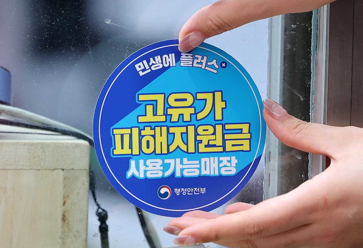 고유가 피해지원금 1차 지급이 시작된 지난달 27일 서울 강서구 남부골목시장에서 한 상인이 '고유가 피해지원금 사용가능매장' 스티커를 붙이고 있다.  / 뉴스1