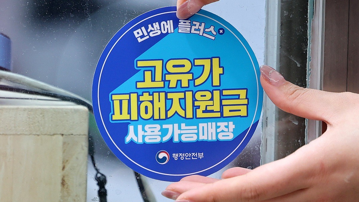한 상인이 '고유가 피해지원금 사용가능매장' 스티커를 붙이고 있다. / 뉴스1