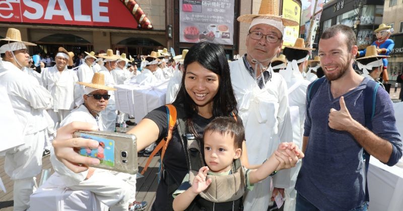 한 외국인 가족이 축제를 홍보하기 위해 보부상 차림으로 도심을 행진하는 상인들과 기념사진을 찍고 있다 / 뉴스 1