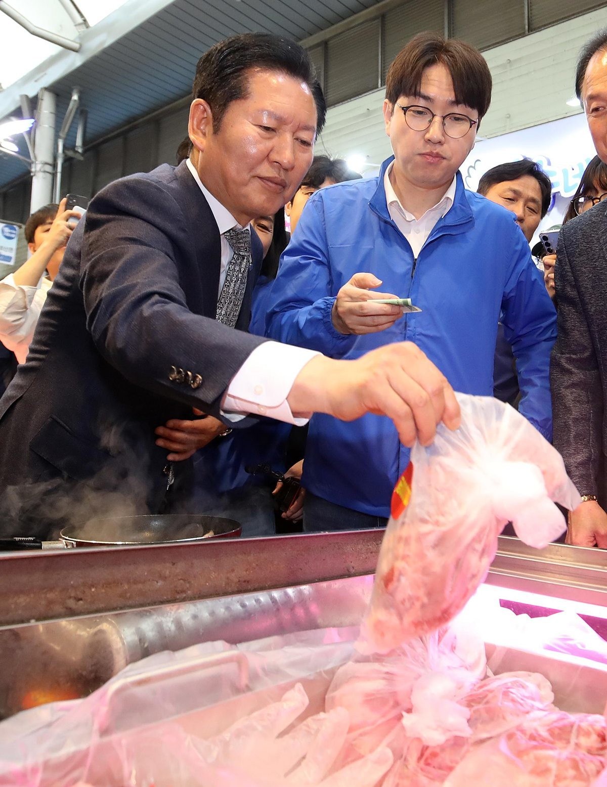 정청래 더불어민주당 대표와 부산 북갑 국회의원 보궐선거에 출마하는 하정우 전 청와대 AI미래기획수석이 지난 3일 부산 북구 구포시장을 찾아 고기를 구입하고 있다. / 뉴스1