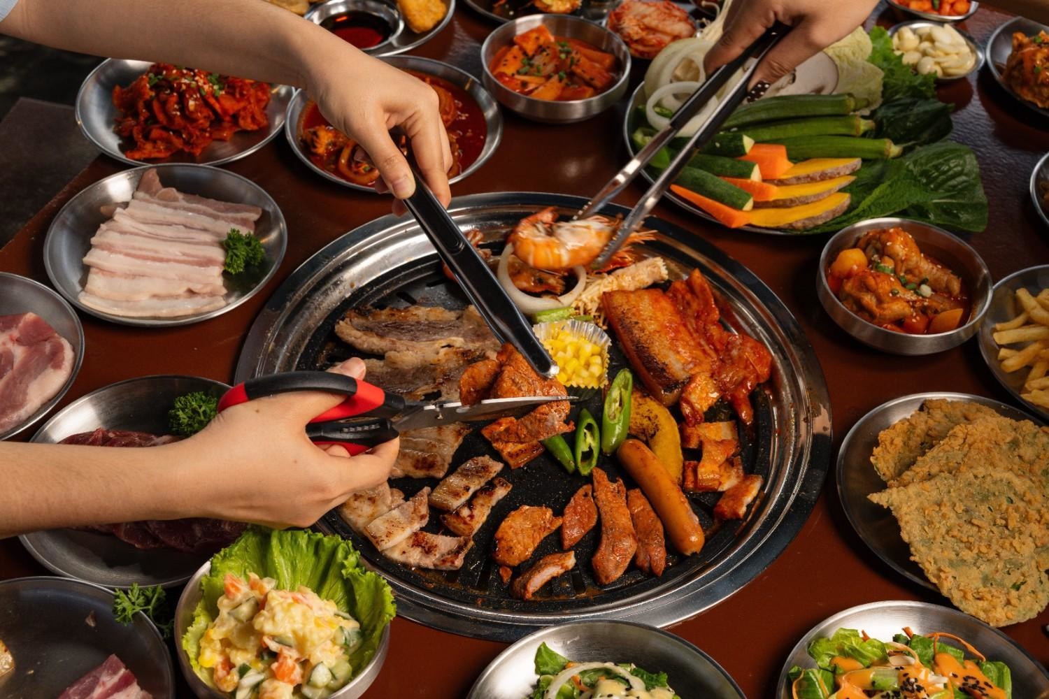 여러 사람이 함께 고기를 굽고 반찬을 나눠 먹는 한국식 바비큐 문화 모습. / 셔터스톡