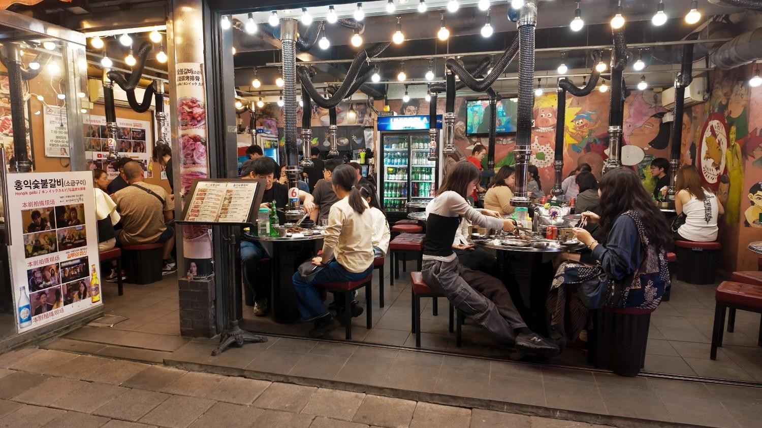 손님들로 가득 찬 한국 고깃집 내부 전경. 테이블마다 함께 식사하는 모습이 눈길을 끈다. / 셔터스톡