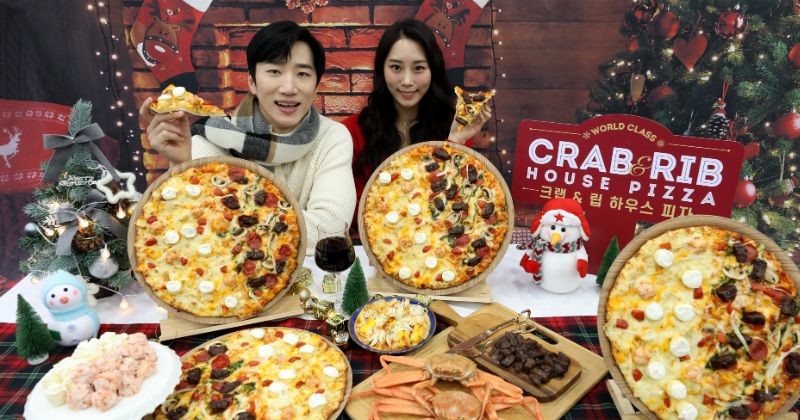 도미노피자 명동점에서 모델들이 피자 한판에 두 가지 맛을 동시에 즐길 수 있는 프리미엄 하프앤하프 '크랩&립 하우스' 피자를 선보이고 있다. / 뉴스 1