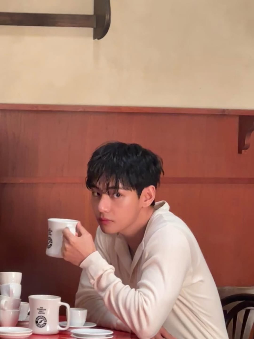 BTS 뷔가 카페에서 머그컵을 든 채 분위기 있는 눈빛으로 카메라를 바라보고 있다. / 뷔 공식 인스타그램