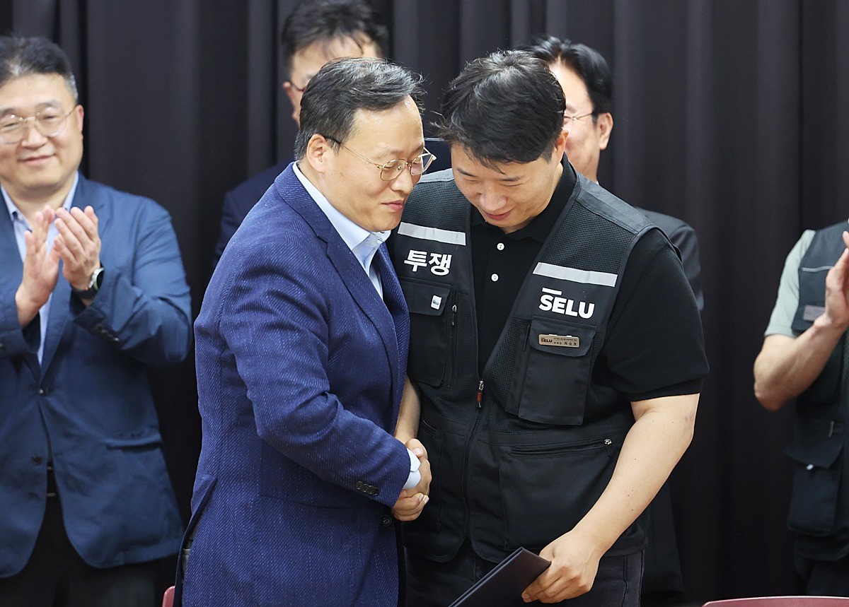 20일 경기도 수원시 장안구 경기고용노동청에서 열린 삼성전자 임금협상을 마친 뒤 여명구 삼성전자 DS(반도체 사업 담당) 피플팀장과 최승호 삼성그룹 초기업노동조합 삼성전자지부 위원장이 잠정 합의한에 서명한 후 손을 맞잡고 있다. / 뉴스1
