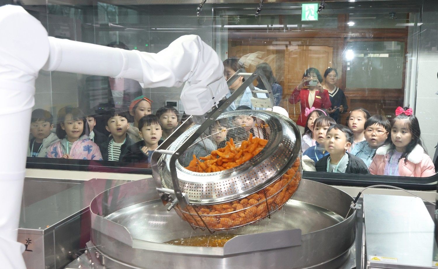 학생들이 학교 급식실에서 자동 튀김 조리 시스템을 지켜보고 있다. / 뉴스1