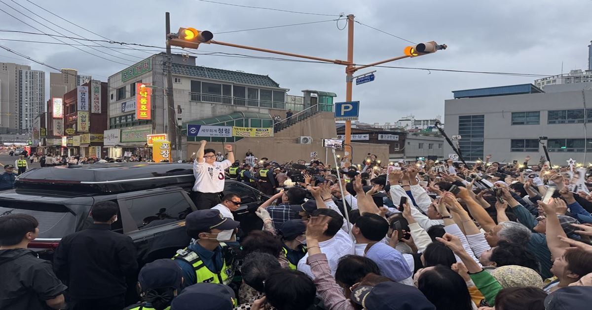 한동훈 무소속 부산 북구갑 국회의원 보궐선거 후보가 21일 부산 북구 구포시장 인근에서 열린 출정식을 마친 뒤 차량 위에서 지지자들에게 손을 들어 인사하며 이동하고 있다. 현장에는 지지자들과 취재진, 경찰 경비 인력이 한꺼번에 몰리며 북새통을 이뤘다.
