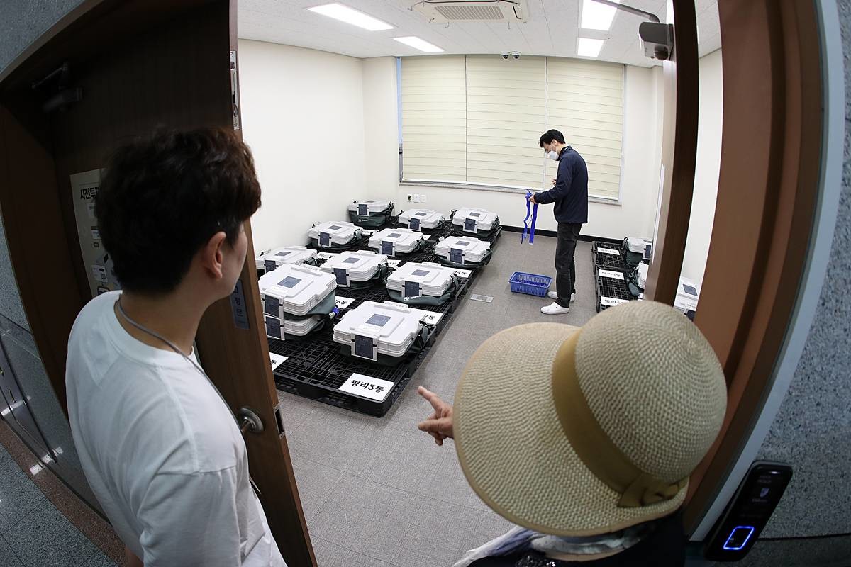 제9회 전국동시지방선거 사전투표가 종료된 전날 오후 대구 서구선거관리위원회 관내사전투표함 보관장소 앞에서 사전투표참관인들이 선관위 관계자들의 투표함 봉함·봉인 과정을 지켜보고 있다 / 뉴스1