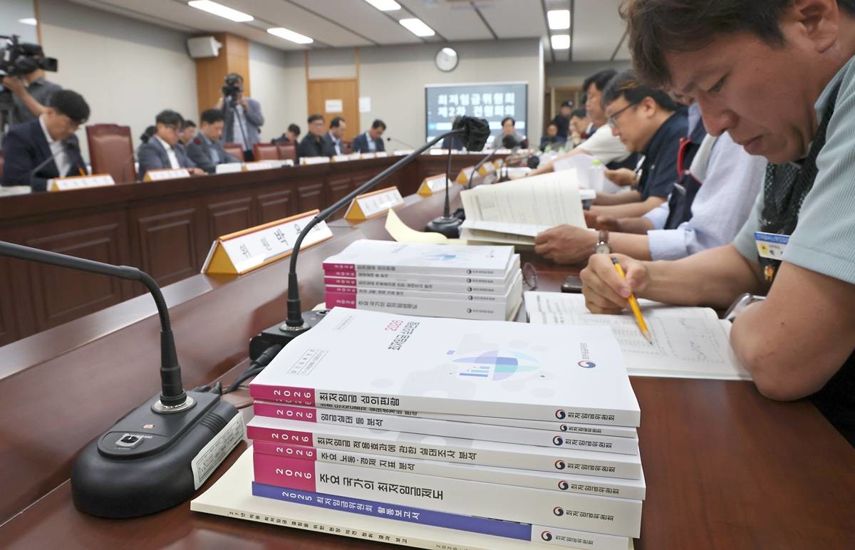 지난 26일 세종시 정부세종청사 최저임금위원회에서 열린 2027년도 최저임금위원회 2차 전원회의에 참석한 근로자위원이 책상에 쌓인 최저임금 지침 자료들을 살펴보며 회의에 임하고 있다 / 뉴스1