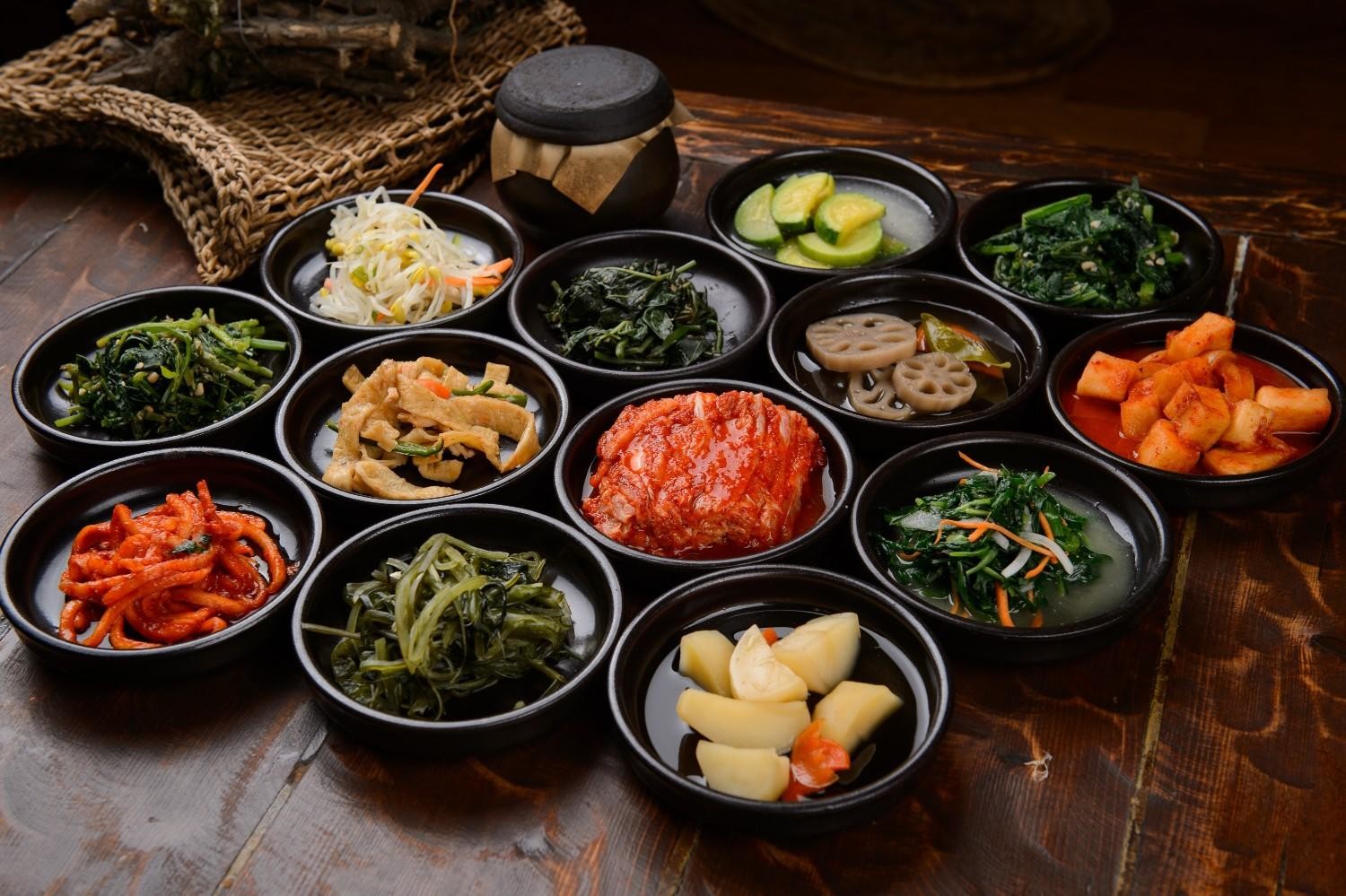 나물, 콩나물, 시금치무침, 연근조림, 김치 등 다양한 반찬이 한 상 가득 차려진 모습. / 셔터스톡