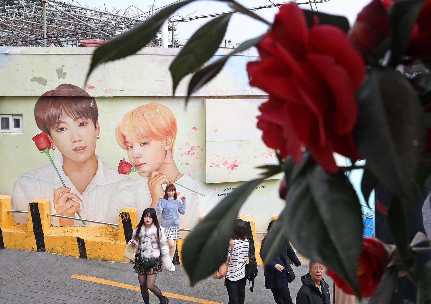 부산 서구 감천문화마을에서 외국인 관광객들이 부산이 고향인 BTS 멤버 정국·지민이 그려진 대형 벽화를 배경으로 기념촬영을 하고 있다. / 2026년 3월 19일자 뉴스1 사진