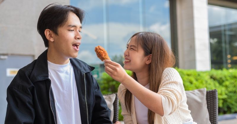젊은 아시아 커플 야외 프라이드 치킨 먹기 / 셔터스톡