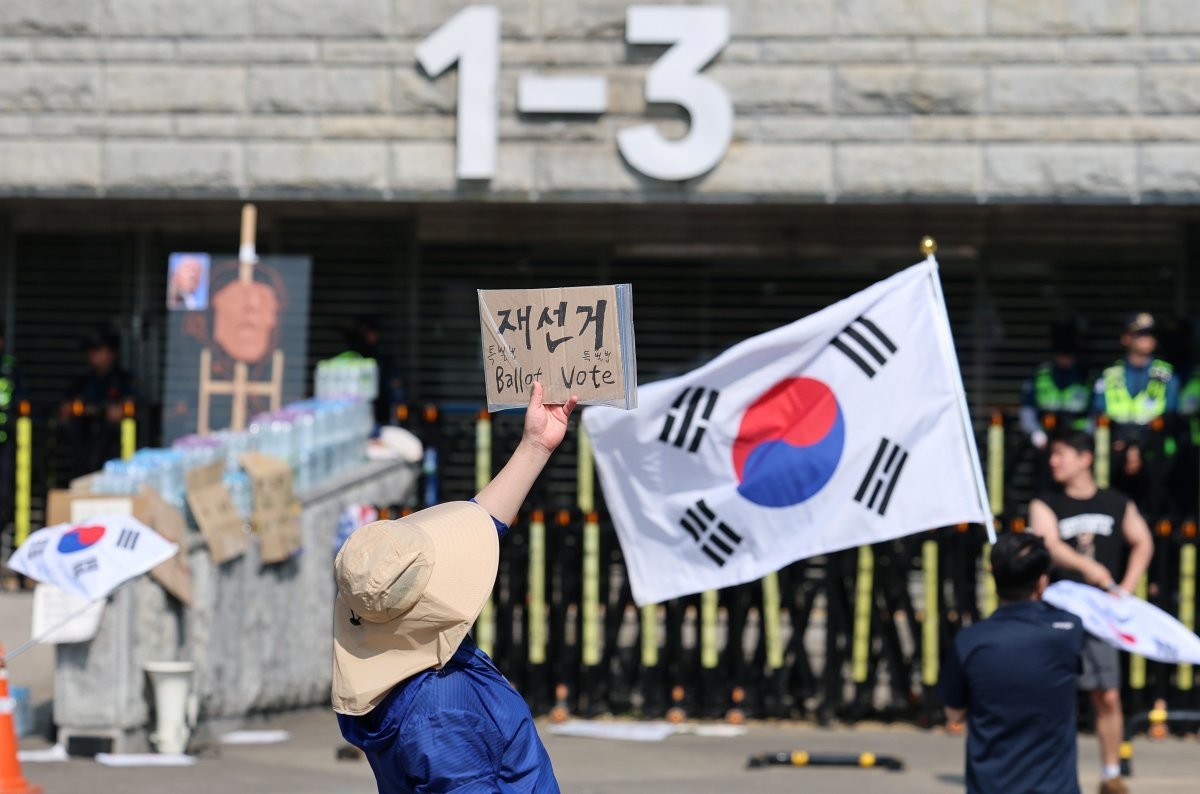 제9회 전국동시지방선거 투표용지 부족 사태를 규탄하는 개표소 봉쇄 시위가 계속된 11일 서울 송파구 올림픽공원 핸드볼경기장 앞에서 시위대가 재선거를 요구하는 피켓을 들고 있다. / 뉴스1