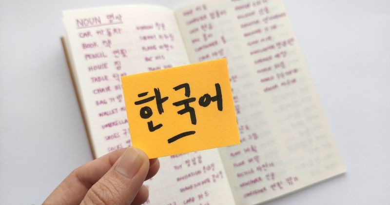 끈적끈적한 노트 위의 한국어는 한국어를 뜻하는데 한국동사가 가득한 수첩을 배경으로 하고 있다. / 셔터스톡