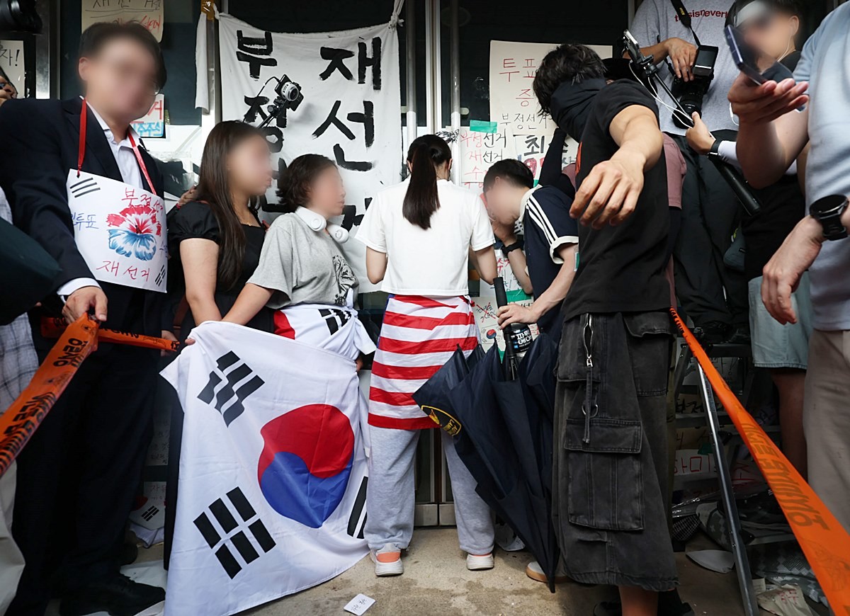 6·3 지방선거 투표용지 부족 사태로 시작한 서울 송파구 올림픽공원 핸드볼경기장 일대 '개표소 봉쇄 시위'가 이어지는 가운데 지난 16일 한 여성 시위 참가자가 대한체육회 등 입주 단체 관계자들의 진입을 홀로 막아서고 있다. 기사 이해를 돕기 위한 자료 사진. 일부 보수 성향 커뮤니티에서는 잠실 개표소 진입을 홀로 막은 여성 시위 참가자 A 씨를 '올림픽공원 잔다르크'의 줄임말인 '올다르크'라고 부르며 추앙하고 있는 상황이다.     / 연합뉴스
