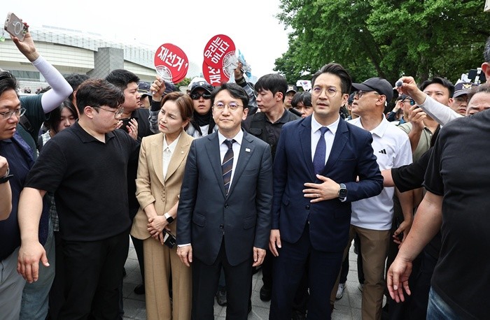 임오경, 전용기, 천준호 더불어민주당 의원이 17일 서울 송파구 올림픽공원 핸드볼경기장 앞에서 투표용지 부족 사태를 규탄하는 시민들에게 항의를 받으며 이동하고 있다. 2026.6.17/뉴스1