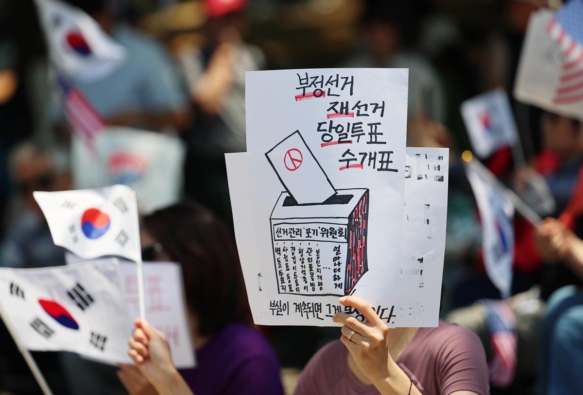 6·3 지방선거 투표용지 부족 사태를 규탄하는 개표소 봉쇄 시위가 11일째 이어진 지난 15일 서울 송파구 올림픽공원 핸드볼경기장 앞에서 참가자들이 태극기를 흔들며 '부정선거 재선거' 구호를 외치고 있다. / 뉴스1