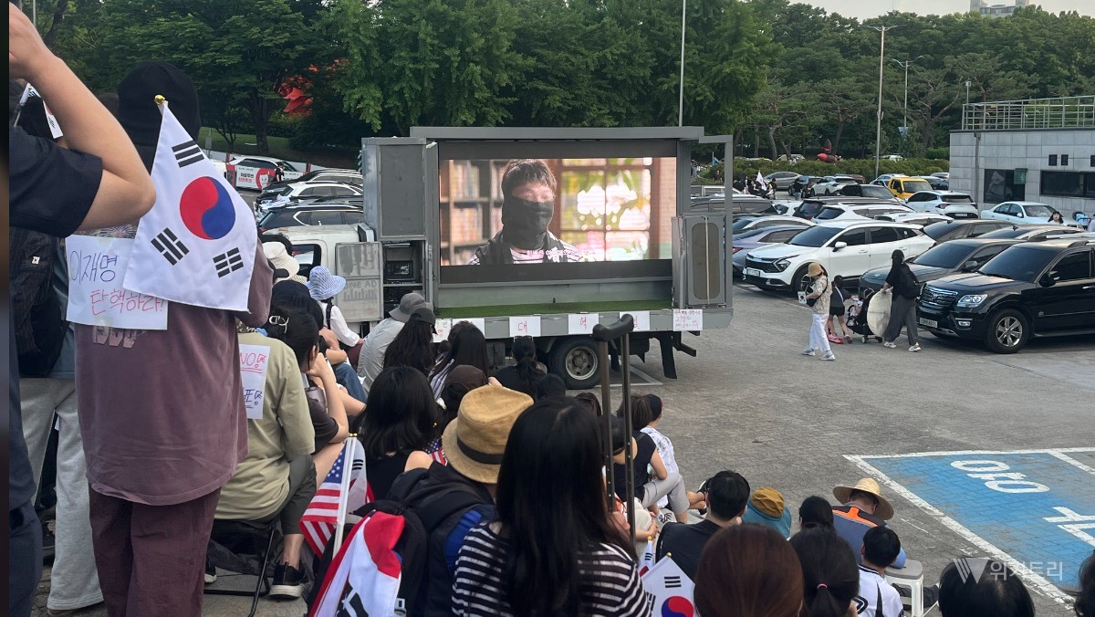 올림픽공원 집회 현장에 모인 시민들이 차량 앞에 서서 부정선거 의혹을 다룬 다큐멘터리를 지켜보고 있다. / 위키트리