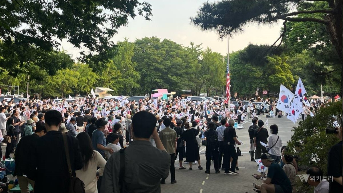 올림픽공원 핸드볼경기장 인근 광장에 모인 시민들이 손팻말을 들고 구호를 외치고 있다. / 위키트리