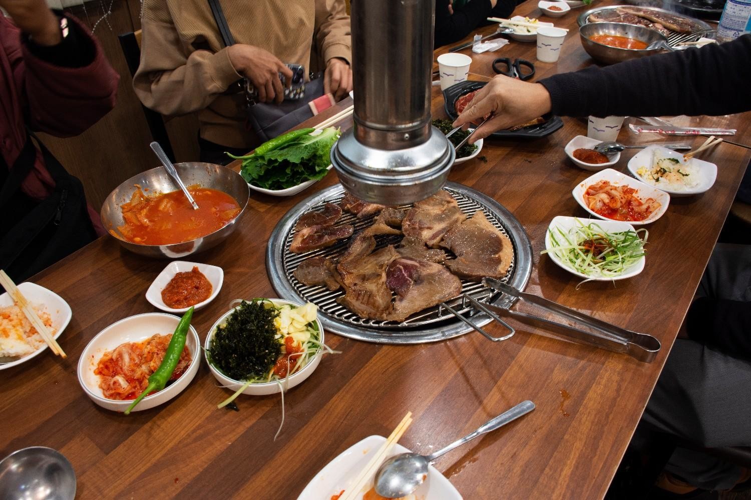 한국 고깃집에서 고기와 함께 다양한 밑반찬이 제공되는 모습. / 셔터스톡