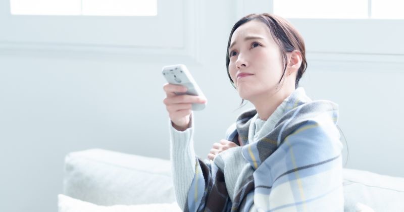 거실에서 에어컨을 사용 하 여 오한이 매력적인 아시아 여자 / 셔터스톡