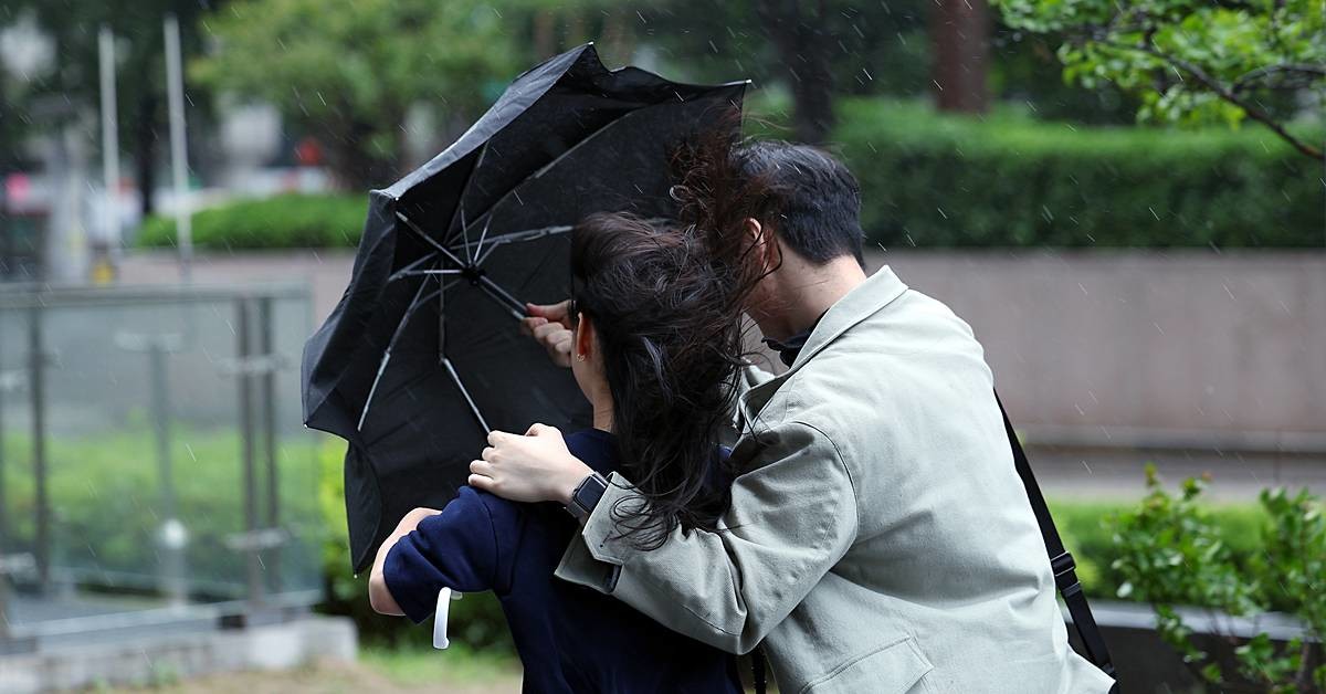 도심을 지나는 한 시민들이 강한 바람에 위태로운 모양의 우산에 의지한 채 발걸음을 재촉하고 있다 / 뉴스1