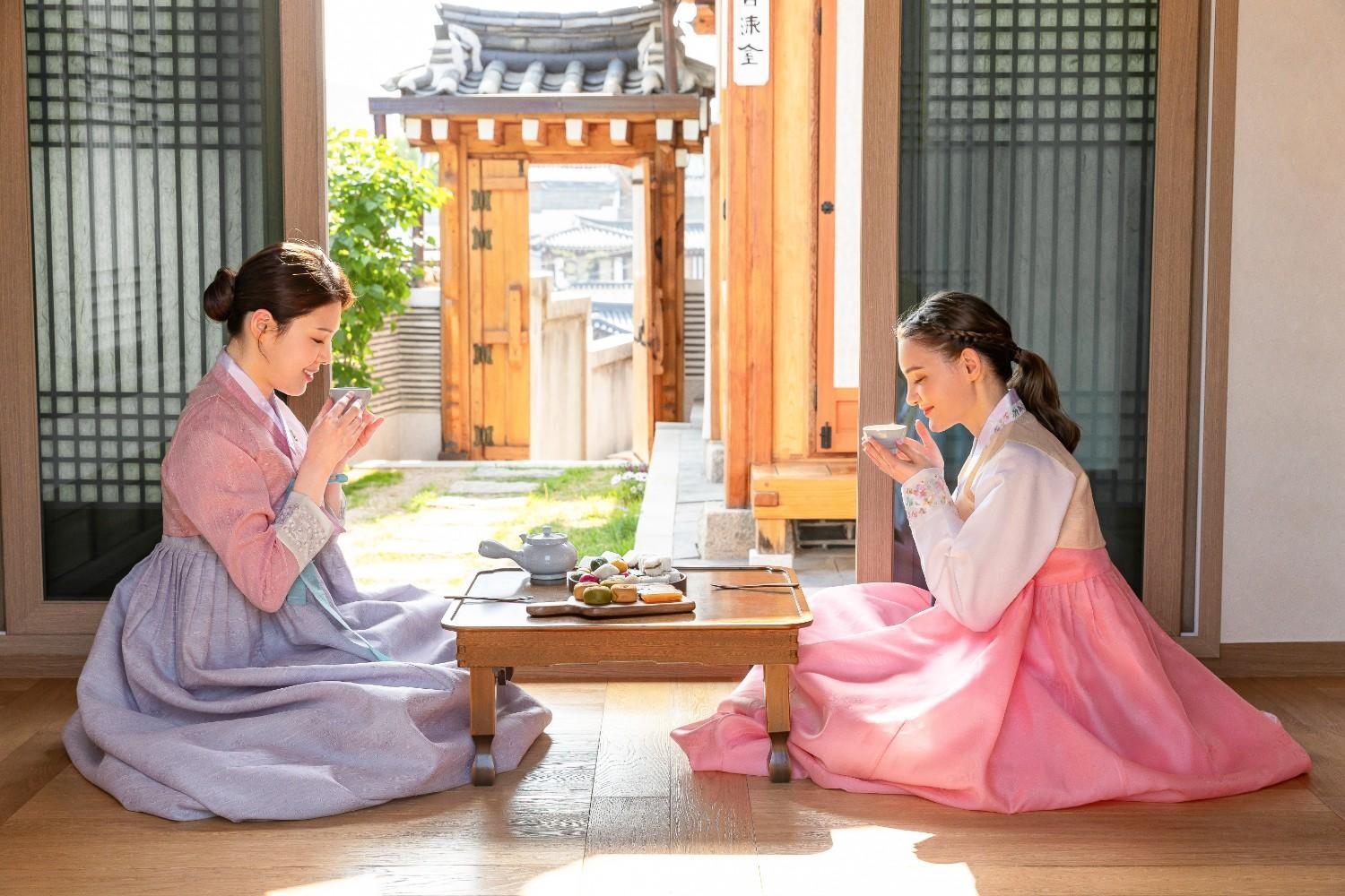한복을 입은 두 사람이 한옥에서 차를 마시고 있다. / 셔터스톡