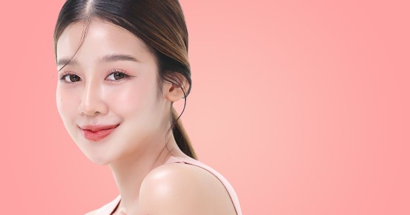 맑고 은은한 광채 피부와 자연스러운 핑크 메이크업을 연출한 여성 모델이 카메라를 향해 미소 짓고 있다. / 셔터스톡