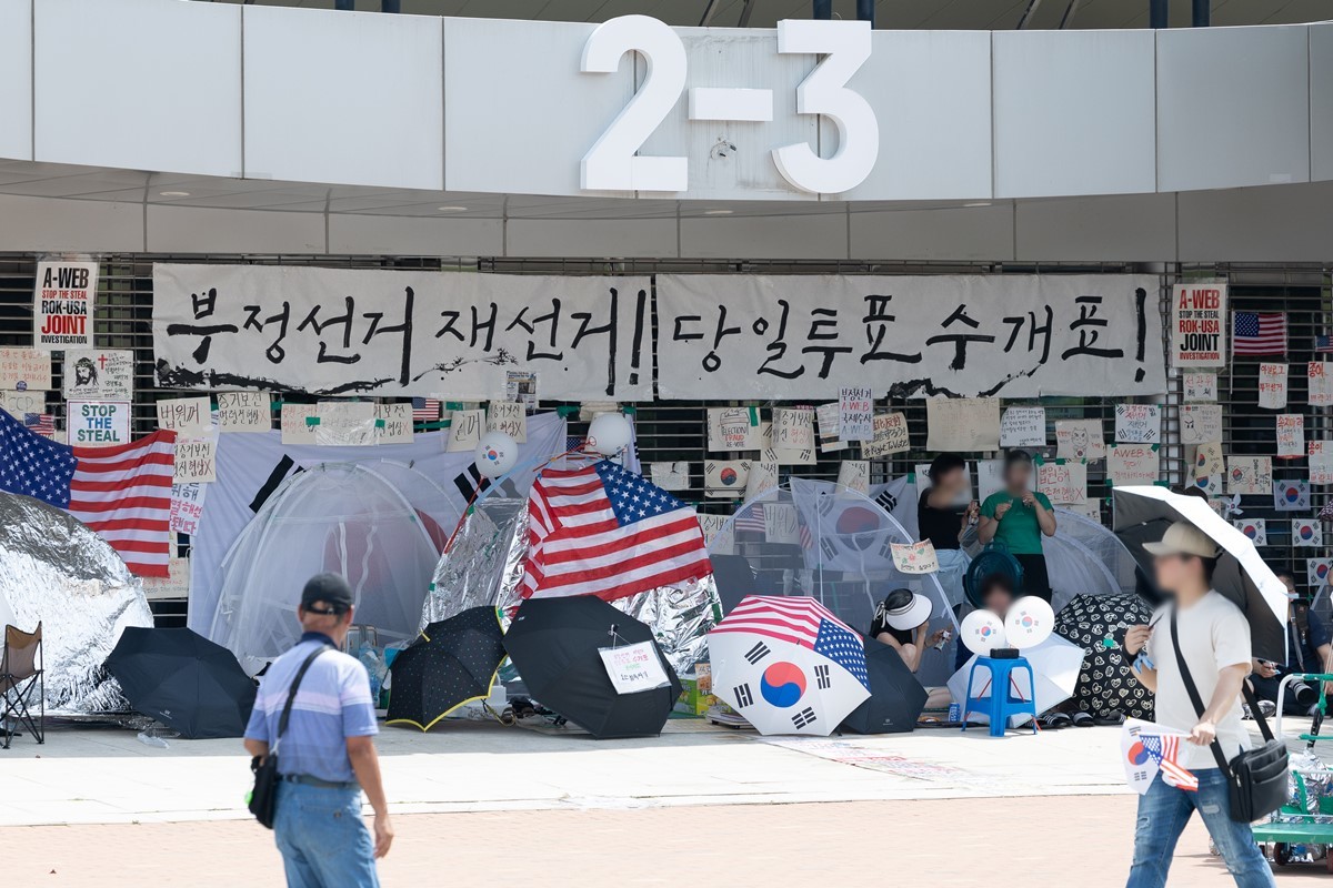 6·3지방선거 이후 한 달 넘게 개표소 봉쇄 시위가 계속되고 있는 17일 서울 송파구 올림픽공원 핸드볼경기장 입구 앞을 시민들이 지나고 있다. 기사 이해를 돕기 위한 자료 사진. 22일 연합뉴스 보도에 따르면 서울 송파경찰서는 최근 서울 송파구 올림픽공원 내 정자에서 정체불명의 흰 가루가 담긴 비닐봉지를 발견했다. 이 정자는 '잠실 개표소 봉쇄 시위'가 벌어지고 있는 핸드볼경기장에서 약 300ｍ 떨어진 곳에 있는 것으로 파악됐다.     경찰은 마약류 여부를 더욱 정밀하게 확인하기 위해 국립과학수사원(국과수)에 검사를 의뢰한 상태다.        / 뉴스1