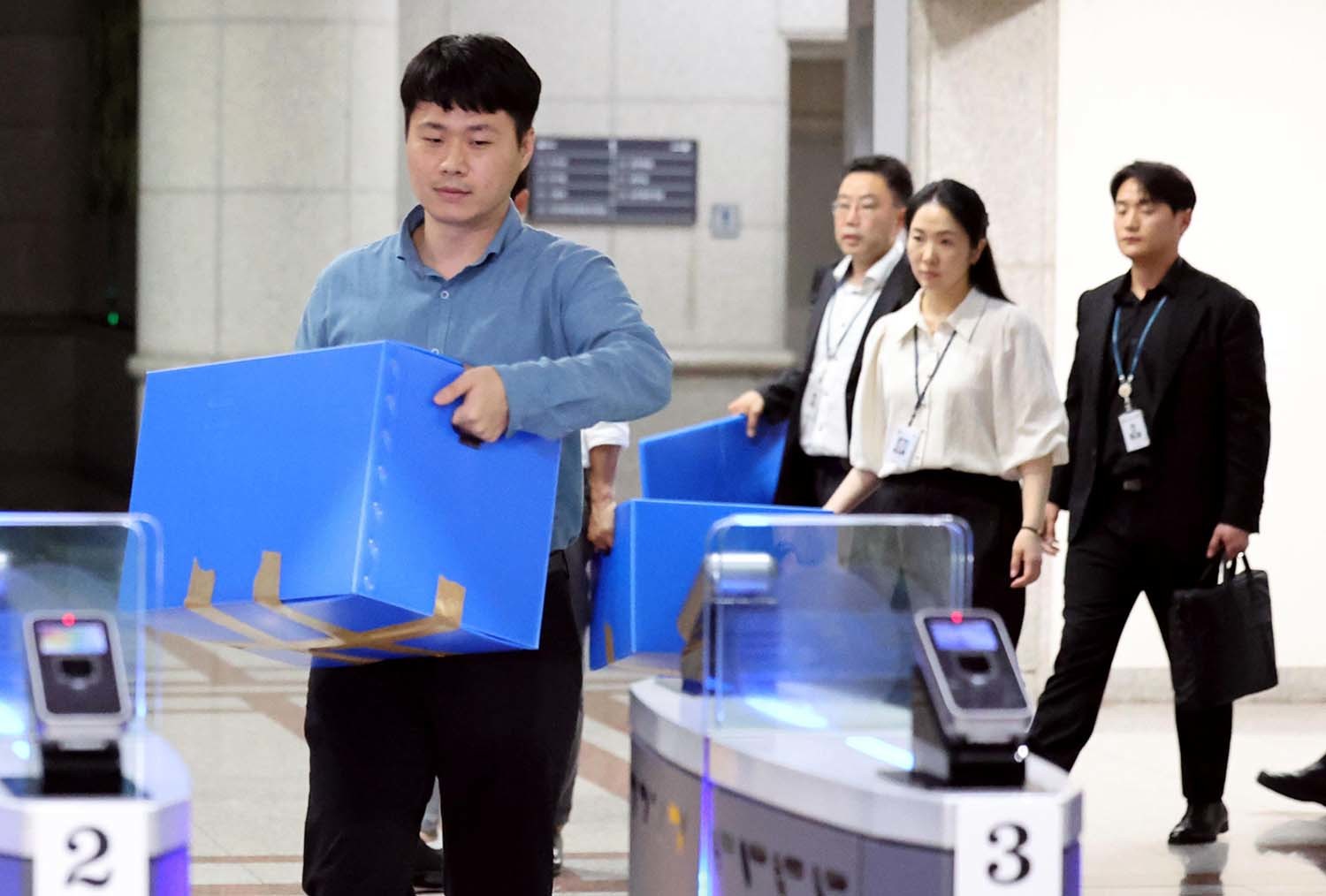 6·3 지방선거 투표용지 부족 사태를 수사 중인 검·경 합동수사본부 관계자들이 23일 오후 경기 과천시 중앙선거관리위원회에 대한 압수수색을 마친뒤 압수상자를 들고 나서고 있다. 이날 검·경 합동수사본부는 선거관리위원회 관계자들의 투표율 통계 조작 정황을 포착해 중앙선관위와 경기도선관위 등에 대한 압수수색에 나섰다. / 뉴스1 (공동취재)