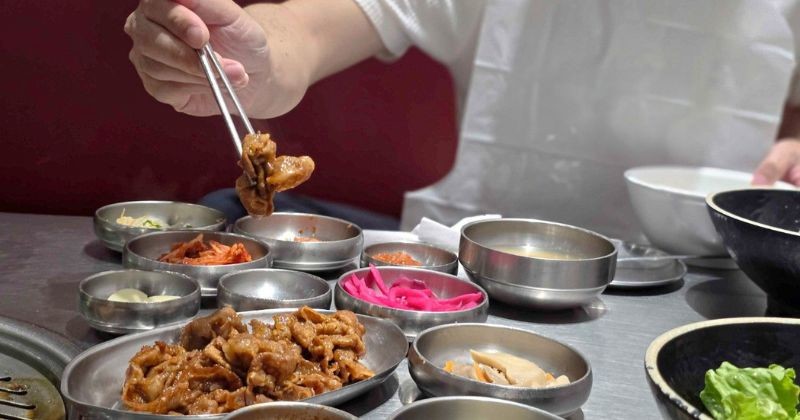 한 식당에서 손님이 다양한 밑반찬과 함께 고기 요리를 먹고 있다. / 셔터스톡