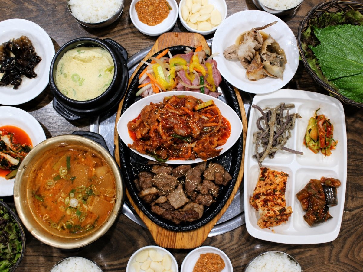 농원숯불왕갈비의 점심특선 정식 한 상. 돼지불백과 제육볶음, 훈제오리, 찌개, 계란찜, 공기밥 등이 함께 제공되며, 사진은 AI로 화질을 개선했다. / 네이버 플레이스 업체 등록 사진