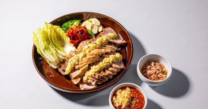 이것은 한국의 전통 음식인 보쌈입니다. 부드러운 수육을 올린 삼겹살에 걸쭉하고 크리미한 노란색 마늘 소스를 얹어 '마늘 보쌈'이라는 이름을 붙였다. / 셔터스톡