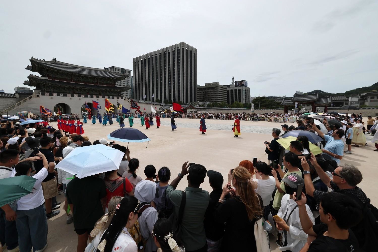 : 서울 경복궁을 찾은 외국인 관광객들이 양산을 쓴 채 수문장 교대의식을 관람하고 있다. / 뉴스1