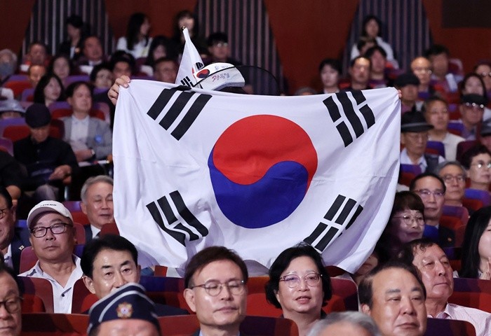 15일 서울 종로구 세종문화회관에서 열린 제81주년 광복절 경축식에서 한 참석자가 이재명 대통령의 경축사가 끝나자 태극기를 펼쳐들고 만세를 외치고 있다. 2026.8.15/뉴스1