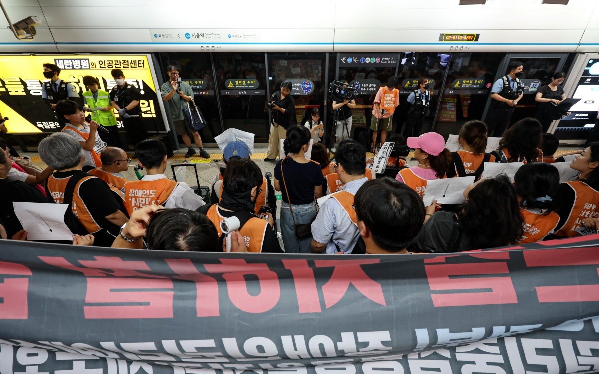 전국장애인차별철폐연대(전장연) 활동가들이 18일 오전 서울 중구 지하철 4호선 서울역에서 '72차 출근길 지하철 탑니다' 시위를 하고 있다. / 뉴스1