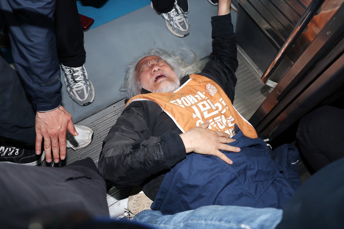 박경석 전국장애인차별철폐연대(전장연) 대표가 서울지하철 4호선 혜화역 동대문 방면 승강장에서 '출근길 지하철 탑니다' 시위를 벌이던 중 이를 저지하던 경찰·서울교통공사 직원 등과 충돌하며 열차 입구에 넘어져 있다. 기사 이해를 돕기 위한 자료 사진 / 뉴스1
