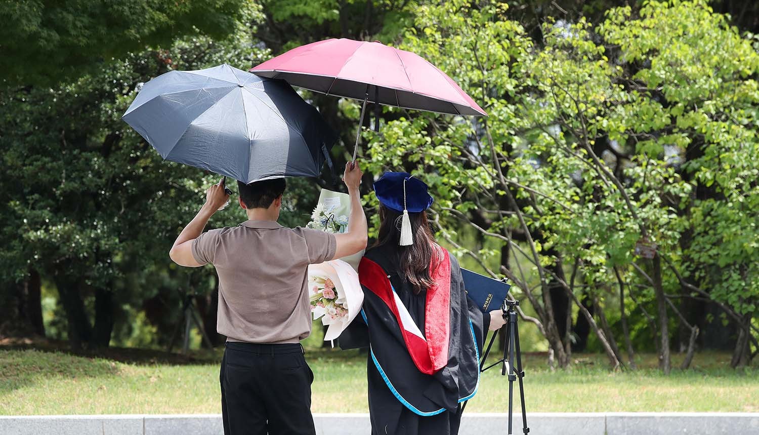 20일 대구 달서구 계명대학교 성서캠퍼스에서 '2025학년도 후기 학위수여식'을 마친 졸업생이 가족과 함께 양산으로 뙤약볕을 가린 채 기념사진을 찍기 위해 걸어가고 있다. / 뉴스1