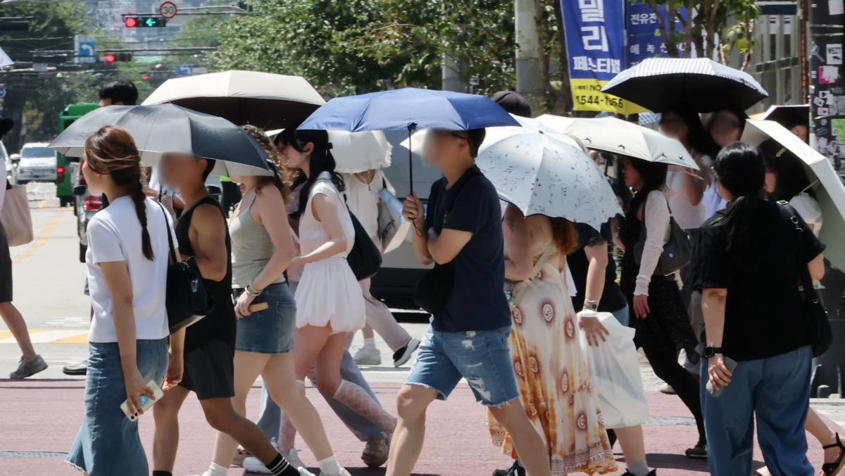 서울 성수동 거리에서 시민 및 외국인들이 양산을 쓰고 이동하고 있다. / 연합뉴스