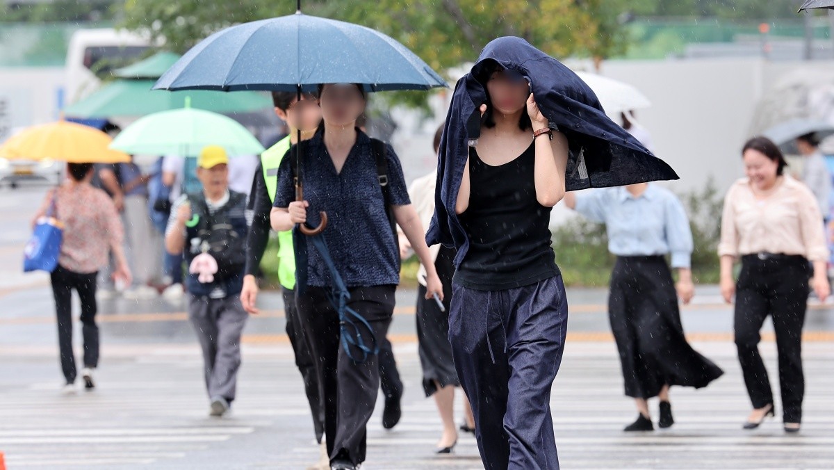 우산을 준비하지 못한 한 시민이 겉옷을 두르고 발걸음을 옮기고 있다. / 뉴스1