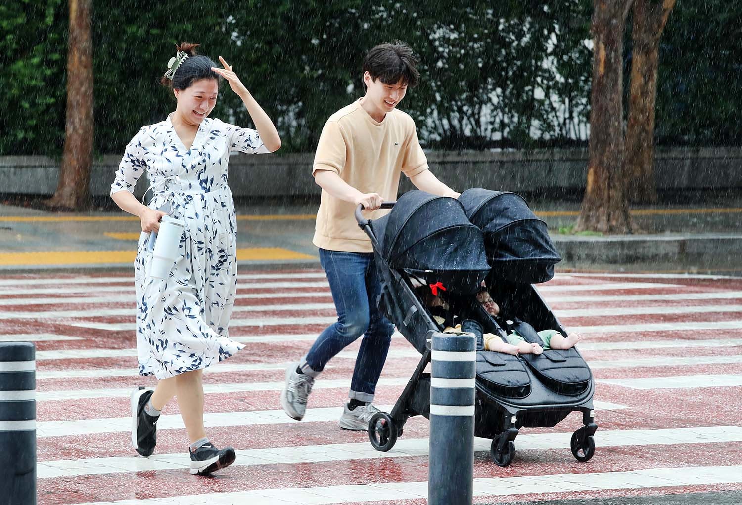 28일 대구 북구 엑스코 앞에서 미처 우산을 챙기지 못한 부부가 유모차를 밀며 횡단보도를 건너고 있다. / 뉴스1