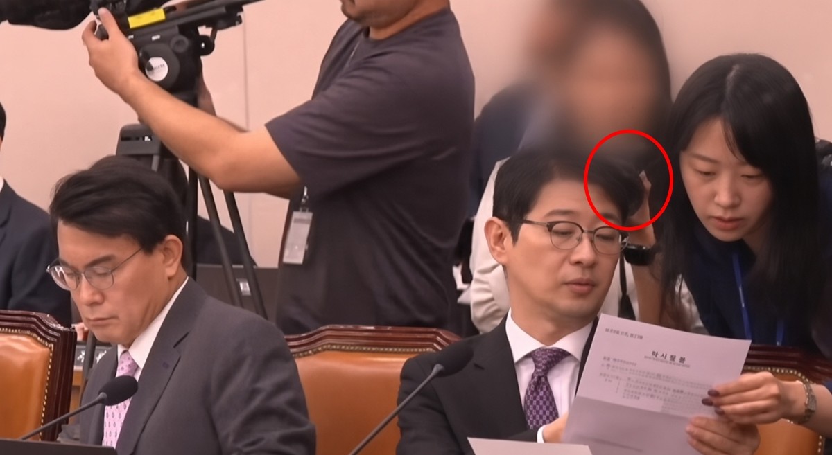 15일 김승원 법무부 장관 후보자의 인사청문회에서 한 여성이 주진우 국민의힘 의원이 들고 있는 서류를 촬영하는 듯한 모습이 포착됐다. 해당 여성은 김 후보자 의원실의 보좌진으로 밝혀졌다. / 유튜브 채널 'JTBC News'