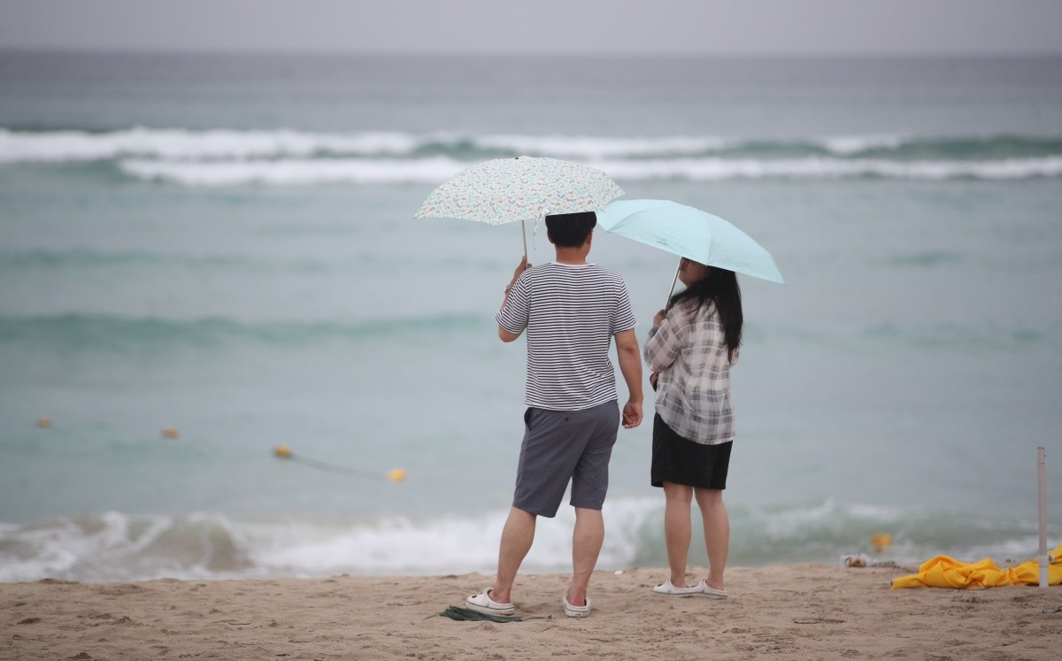 제주시 조천읍 함덕해수욕장에서 우산을 쓴 관광객들이 파도가 이는 바다를 바라보고 있다 / 뉴스1
