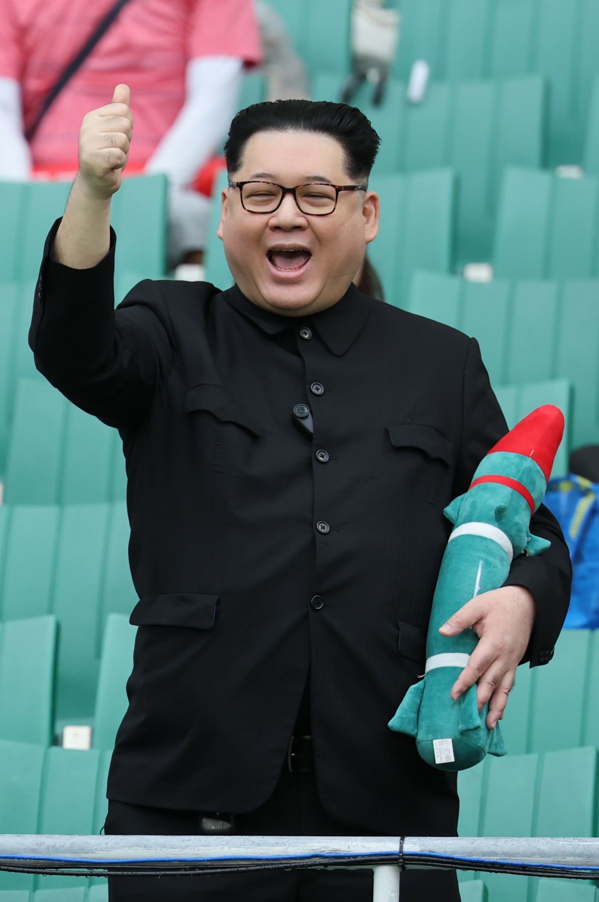 21일 일본 시즈오카 스타디움 에코파에서 열린 2026 아이치·나고야 아시안게임 조별예선 F조 대한민국과 북한의 경기를 찾은 중국계 정치활동가 '하워드X'가 북한 김정은 국무위원장 모습으로 엄지 손가락을 치켜들고 있다 / 뉴스1