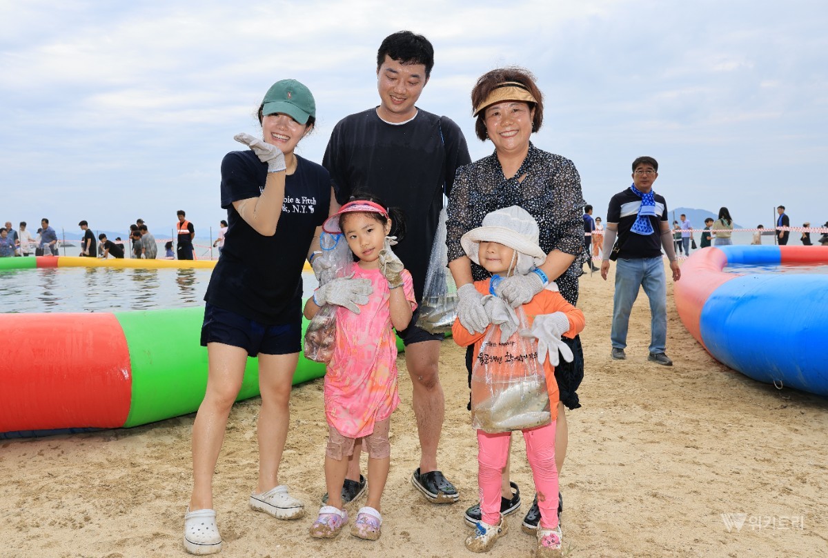 가족이 직접 작은 전어를 들고 환한 미소를 짓고 있다. / 보성군