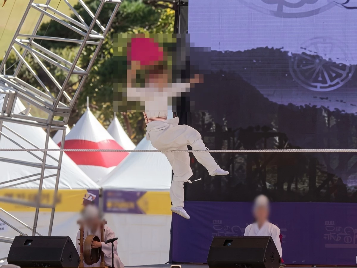 사고 전 줄타기 공연 모습. AI를 활용해 사진 해상도 등을 개선했다. 경기 안성시의 남사당 바우덕이 축제 도중 줄꾼(어름사니) 추락 사고가 발생한 것으로 전해졌다. 3일 연합뉴스 보도에 따르면 전날(2일) 오전 11시 40분쯤 안성시의 바우덕이 축제가 진행되고 있는 안성맞춤랜드에서 줄타기 공연 도중 줄꾼이 약 2.5m 아래 바닥으로 떨어졌다. 당시 사고로 줄타기 공연을 벌인 줄꾼은 병원으로 옮겨져 치료받았으며 지금은 퇴원한 상태인 것으로 전해졌다. 이번 사고는 줄꾼이 줄에 올라서서 공연하던 도중 줄을 고정하는 지지대가 쓰러지면서 발생한 것으로 파악됐다. / 연합뉴스