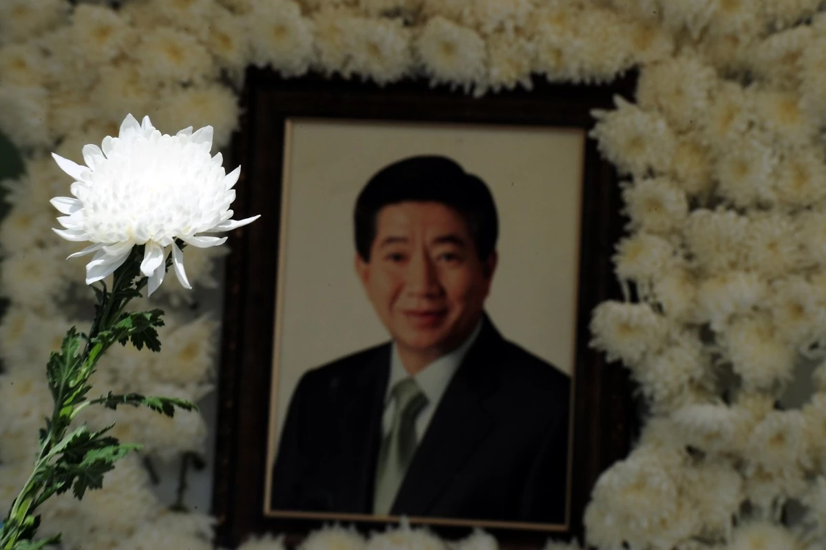 노무현 전 대통령 서거 3주기를 맞은 2012년 5월 23일 오후 서울 대한문 앞에 마련된 추모소를 찾은 한 시민이 들고 있는 국화 너머로 노 전 대통령의 영정이 보인다. / 뉴스1 자료사진