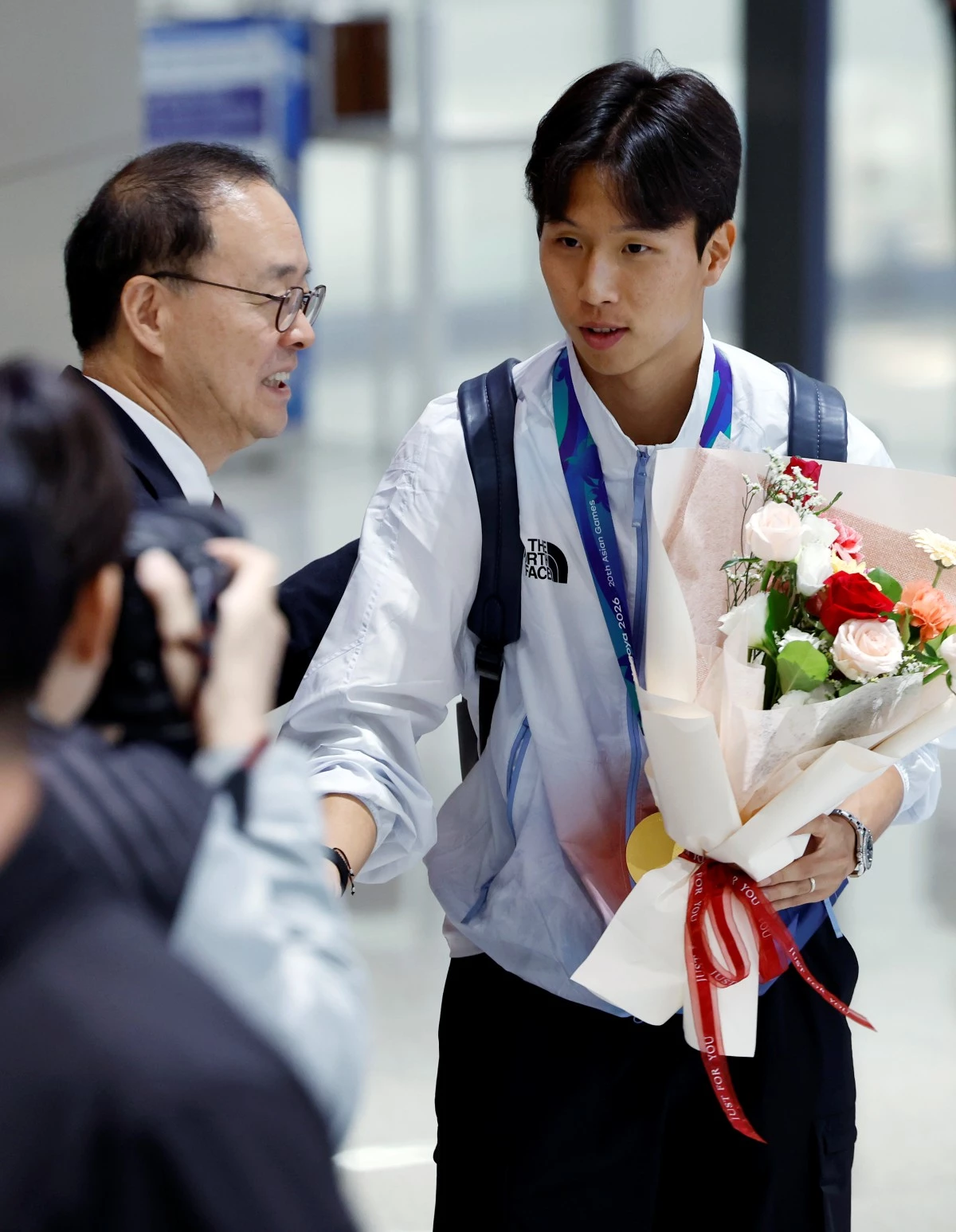 2026 아이치-나고야 아시안게임 남자축구 결승전에서 결승골을 넣은 엄지성이 지난 4일 오후 인천국제공항을 통해 귀국해 이용수 대한축구협회장 직무대행에게 축하 꽃다발을 받고 있다. / 뉴스1